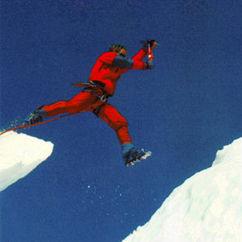 Spěchající horolezec skáče přes ledovcovou puklinu
